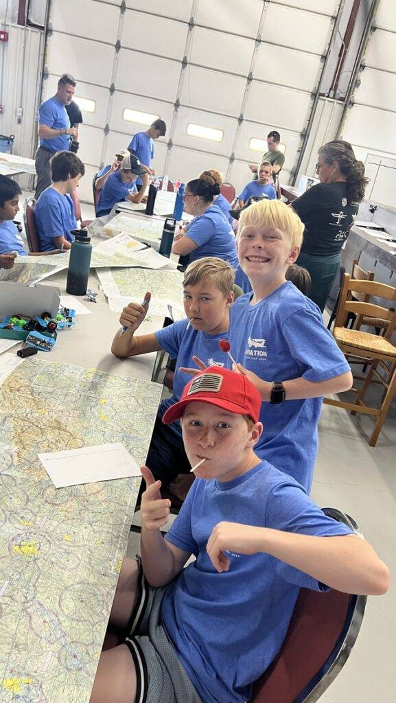 Young people at a CFH aviation program studying aeronautical charts inside an aircraft hangar.