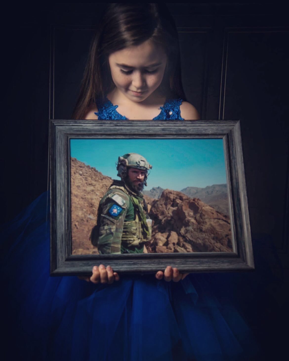 The daughter of Staff Sergeant Liam A. Flynn holds a framed photograph of her father.