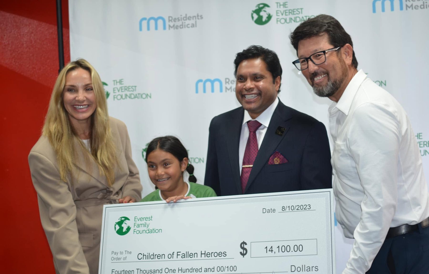 A young participant stands with three adults holding an oversized Everest Family Foundation cheque made out to Children of Fallen Heroes.