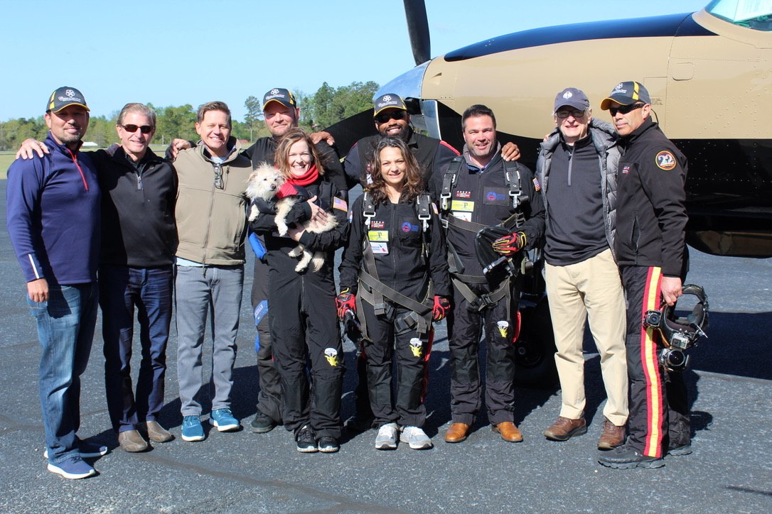 The Harris family standing together with their jump team on the tarmac at Paraclete XP, geared up beside the aircraft before the jump.