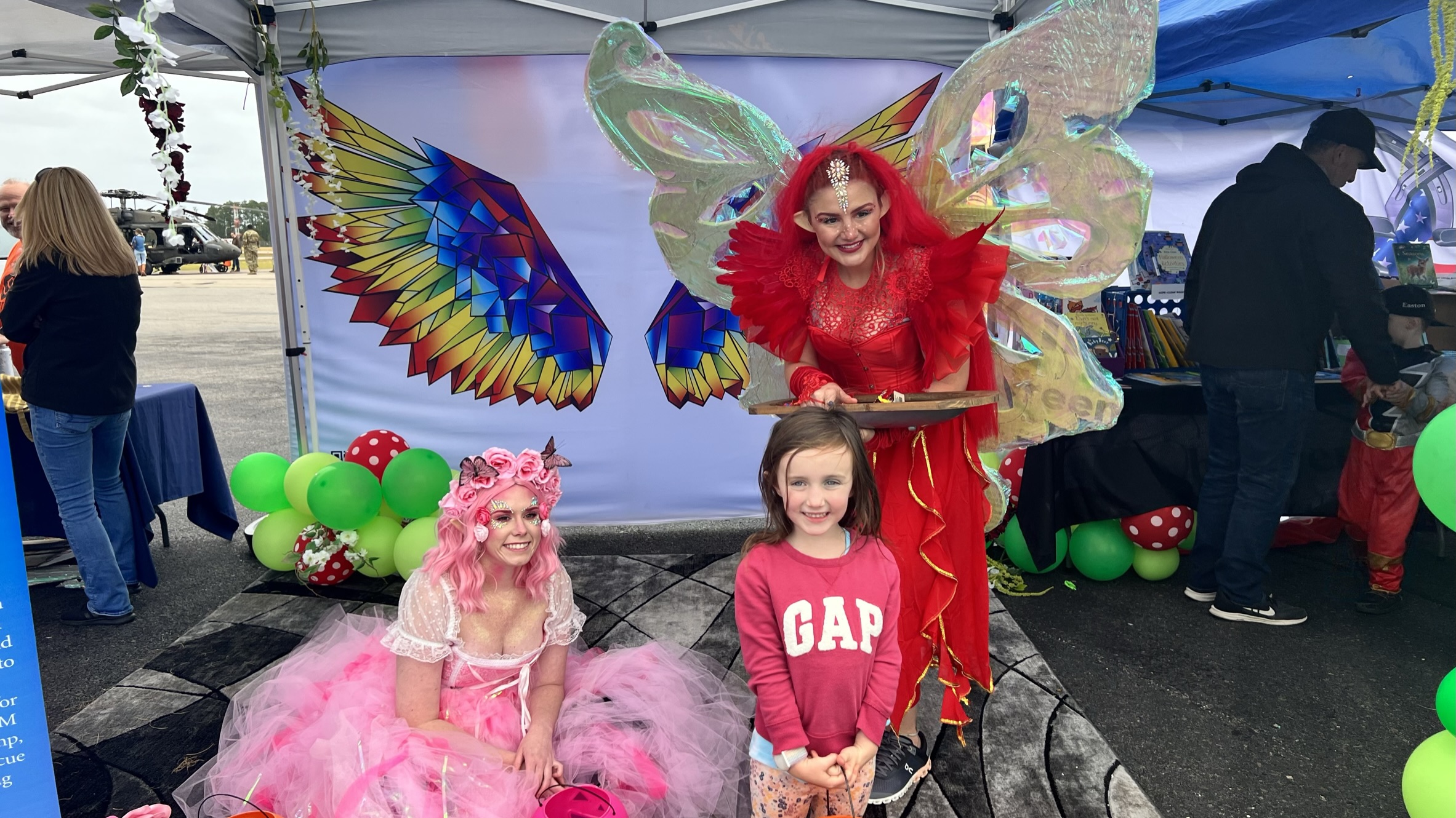 A young girl with costumed performers at a Children of Fallen Heroes community event