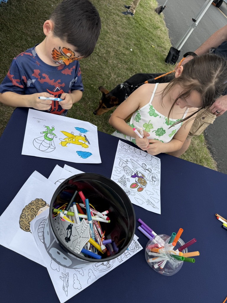 Two students coloring Children of Fallen Heroes aviation art sheets with markers