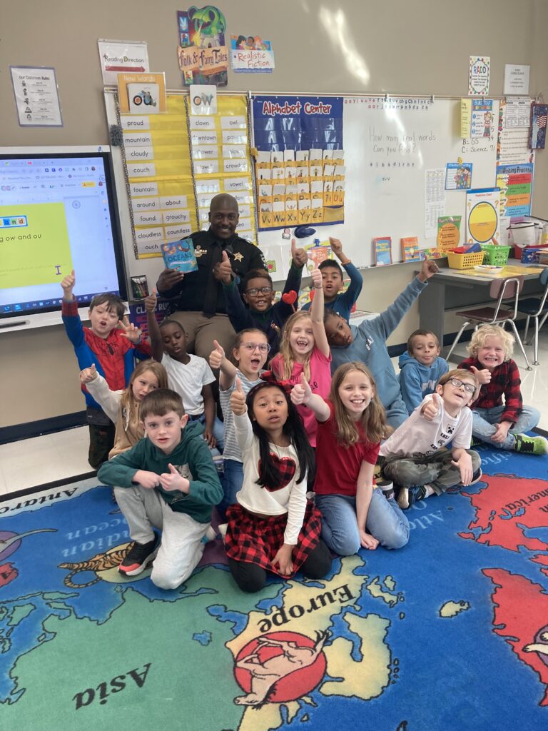 A classroom of students and their teacher cheering during a CFH STEAM visit.