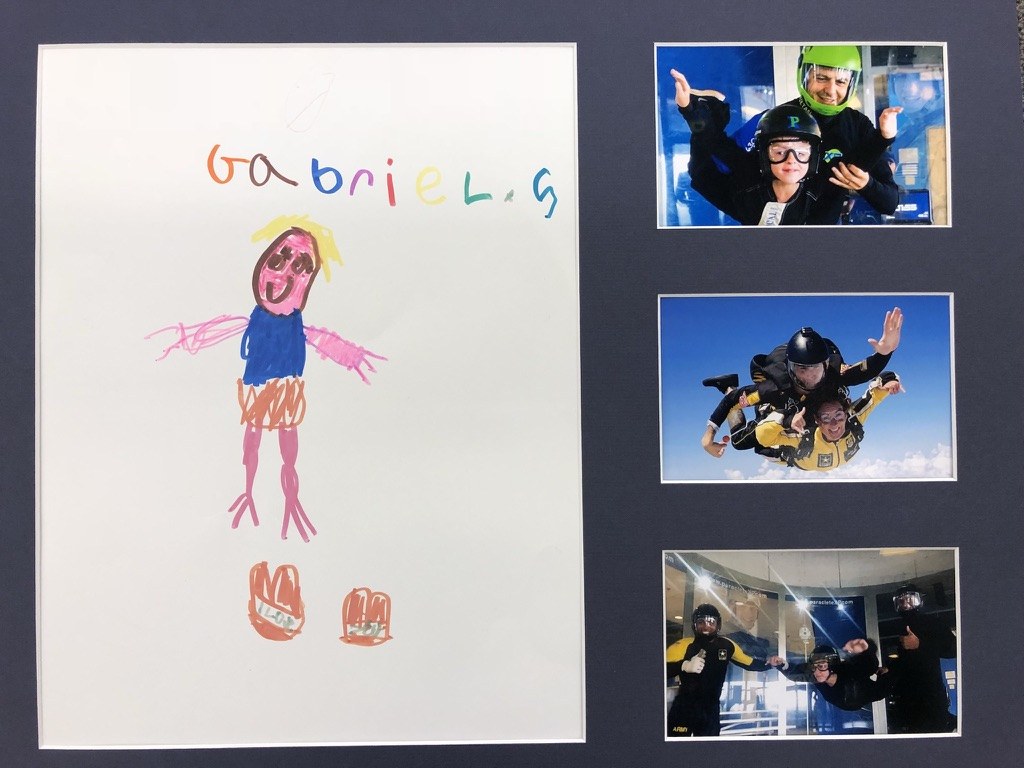 A framed keepsake from Paraclete XP: a child's drawing beside photographs of the boys flying in the wind tunnel and a tandem skydive.