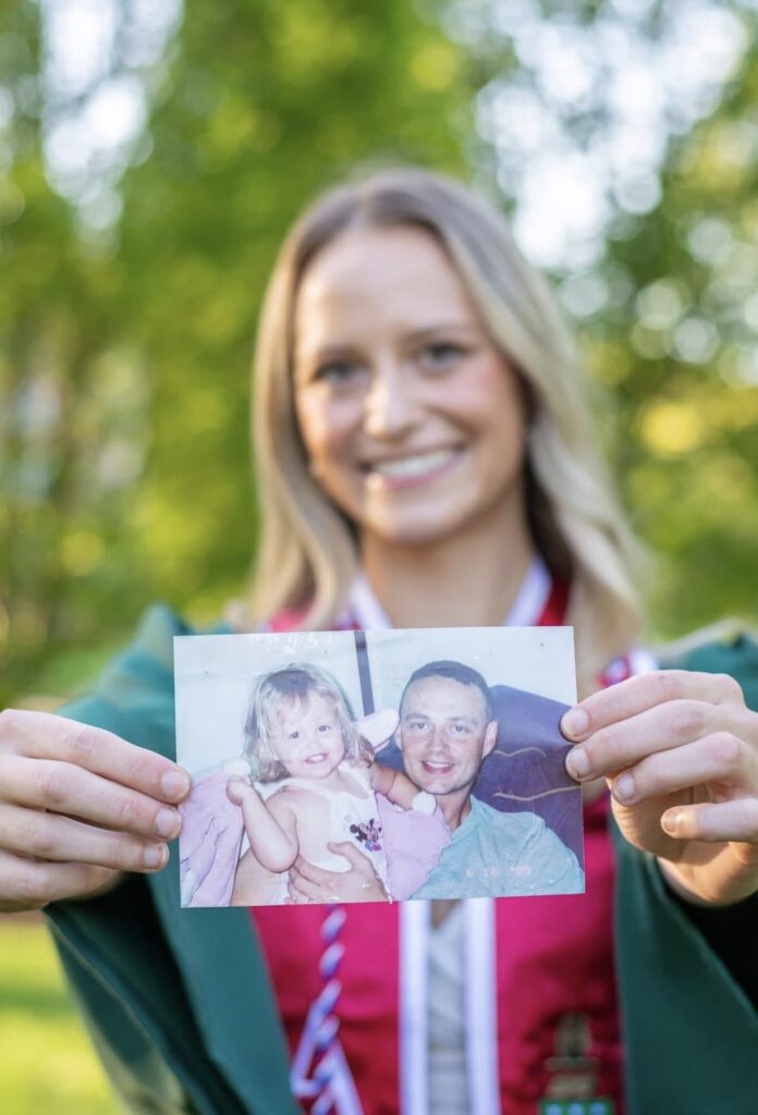 Courtney Dempsey at college graduation holding a childhood photograph with her father, U.S. Army Major Daniel Dempsey.