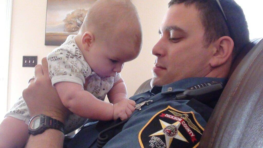 Deputy Richard “Keith” Bellar in uniform holding his infant child.