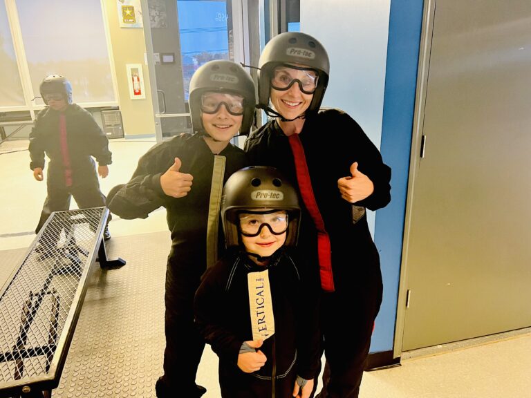 Brandi and her children in flight suits and helmets, giving thumbs up at Paraclete XP.