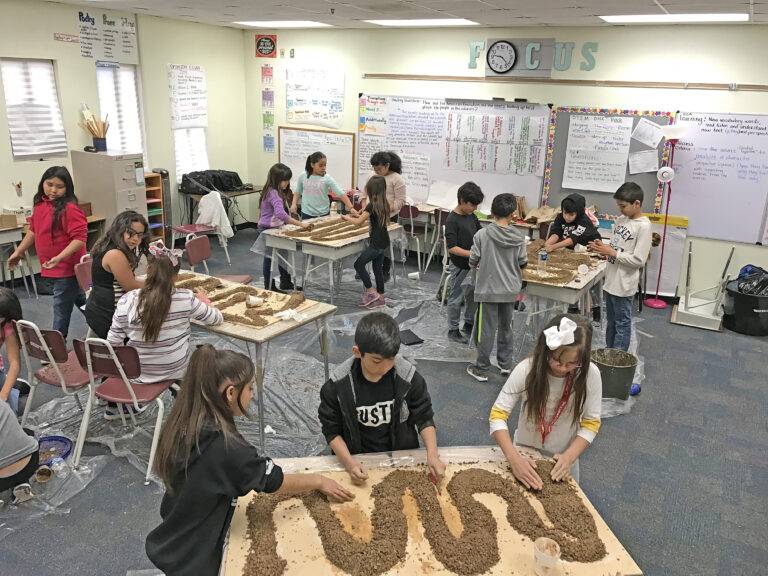 A classroom of elementary students building model BMX tracks out of dirt on their desks during a USA BMX STEM lesson