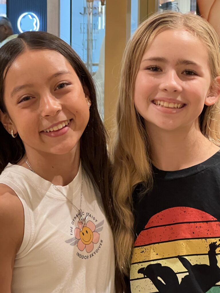 Two young supporters smiling together at the Kendra Scott event.